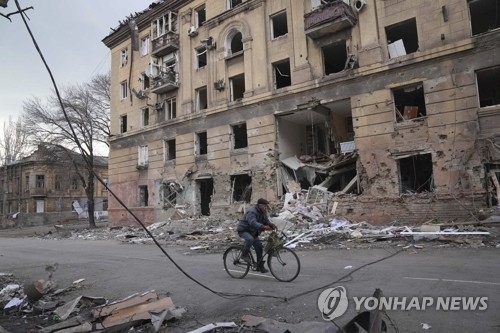 러시아의 폭격으로 파괴된 우크라이나 마리우폴의 아파트 앞을 한 주민이 지나고 있다. 사진=연합뉴스/한중21 제휴사