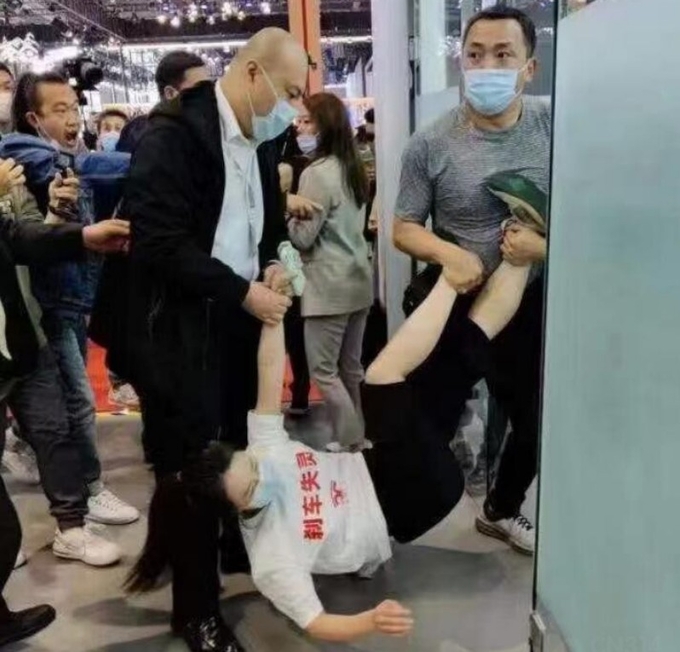 중국테슬라 전시관 관계자들이 , 시위여성소비자를 사무실 끌고가는 가는데 , 다른 참관자들이 항의하고 있다. .
